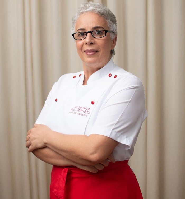Denise Andrade, de dólma branca com a logo da Alquimia de Sabores e avental vermelho