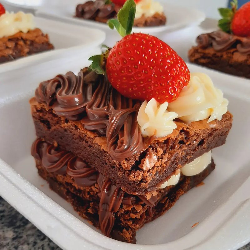 Fatia de bolo de chocolate em camadas, com brigadeiro e um morango no topo