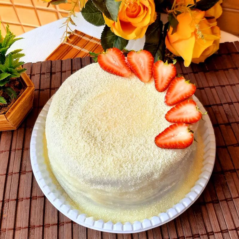 Bolo redondo coberto de coco ralado, decorado com morangos