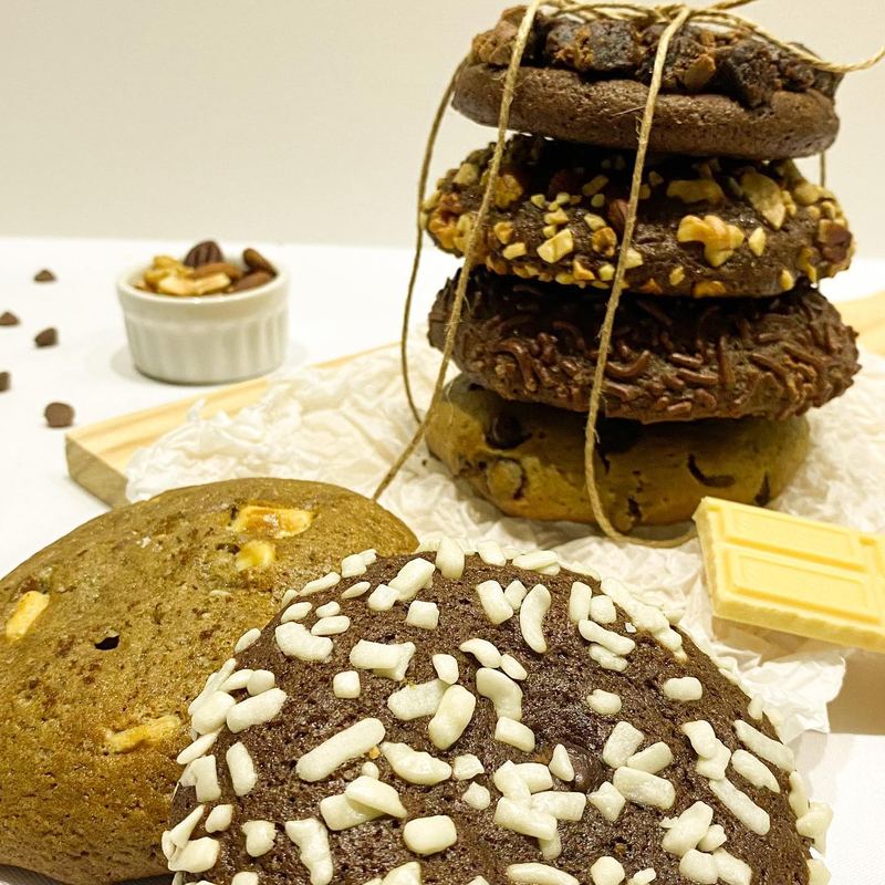 Cookies artesanais empilhados e amarrados com barbante, ao lado de castanhas