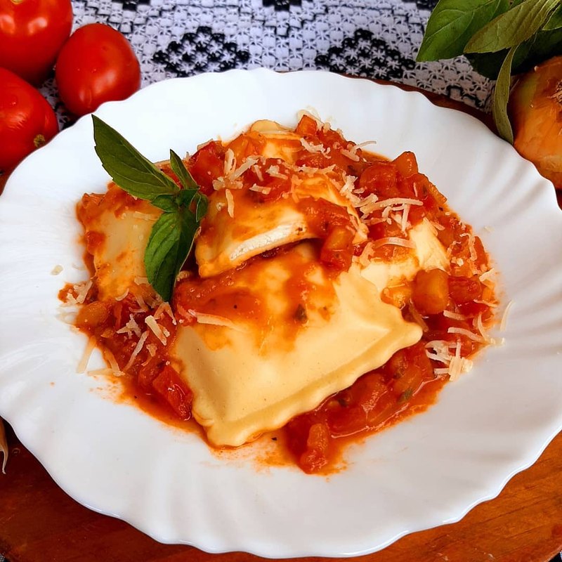 Massa recheada ao molho de tomate, com parmesão ralado e folhas de manjericão