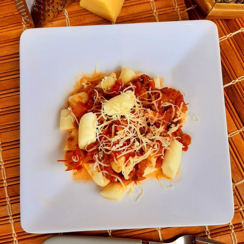 Nhoque à moda em prato quadrado, com molho, parmesão e alho frito