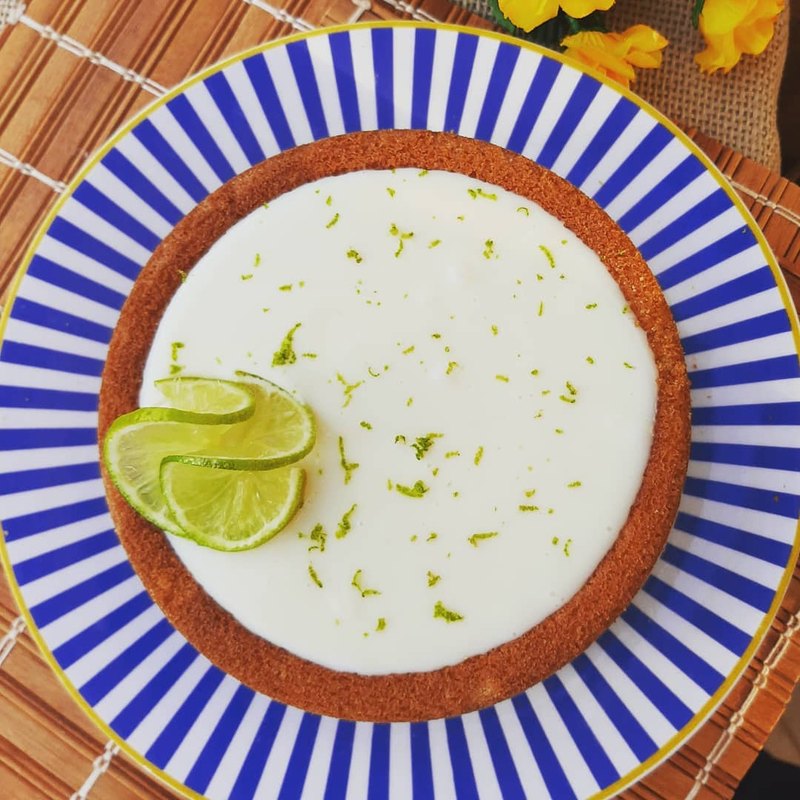 Torta de limão com raspas e rodelas de limão, em prato listrado