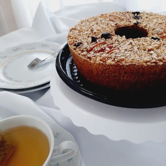Bolo integral de frutas com cobertura de aveia, servido com chá