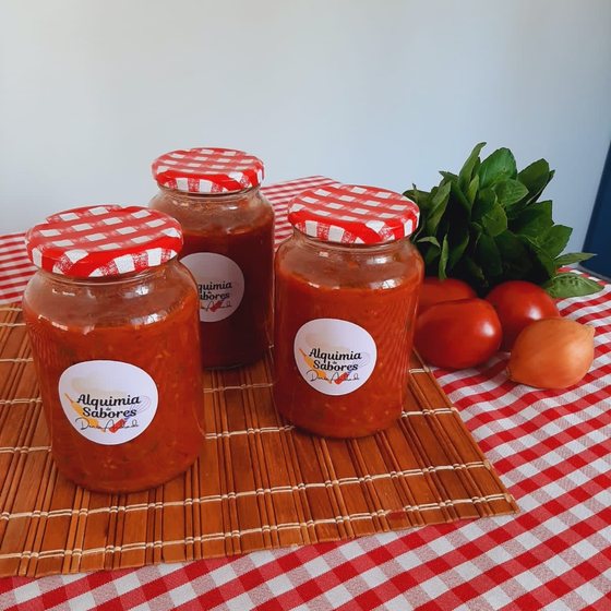 Potes de molho pomodoro com tampa xadrez, ao lado de tomates frescos