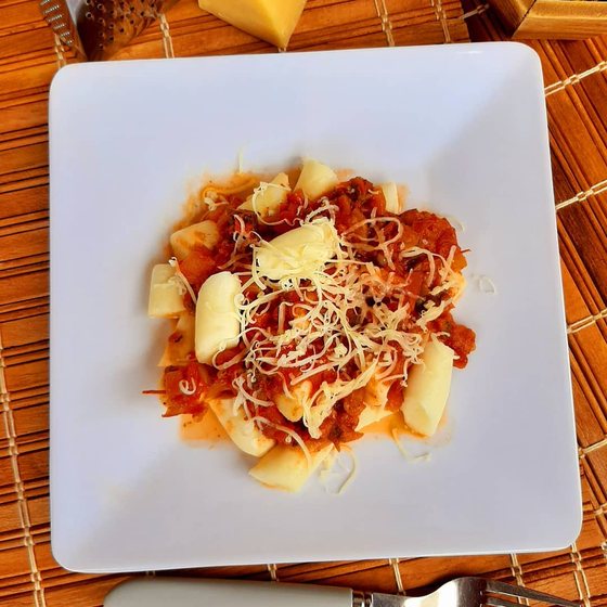 Nhoque à moda em prato quadrado, com molho bolonhesa e parmesão